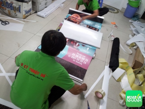 Nhân viên gia công sản phẩm poster PP - lắp sẵn poster vào banner cuốn cho khách hàng